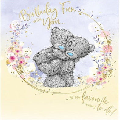 Card with a teddy bear holding flowers and birthday message on a light blue background